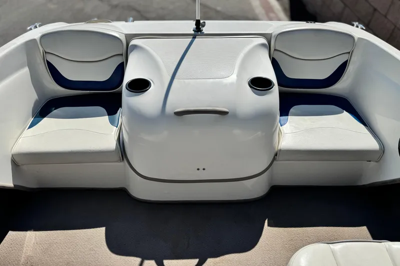 Slide: The Image of 2004 Bayliner 175 Bowrider interior with white and blue seating, cup holders, and storage. - 13