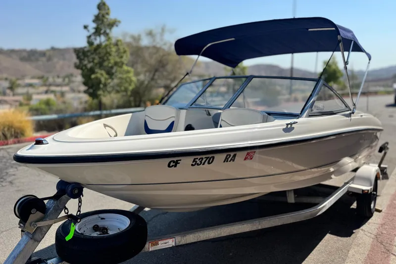 Slide: The Image of 2004 Bayliner 175 Bowrider boat on trailer with blue canopy, parked outdoors. - 3