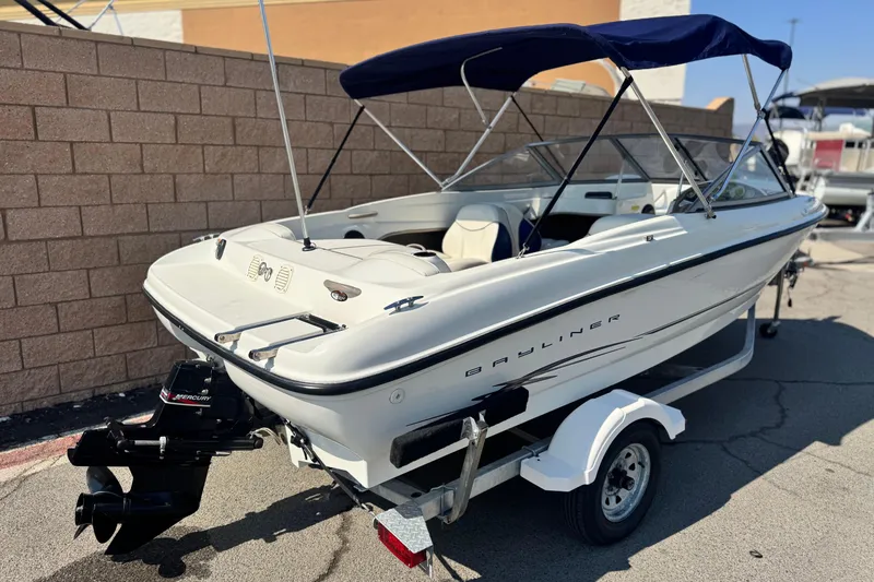 Slide: The Image of 2004 Bayliner 175 Bowrider boat with blue canopy on a trailer. - 5