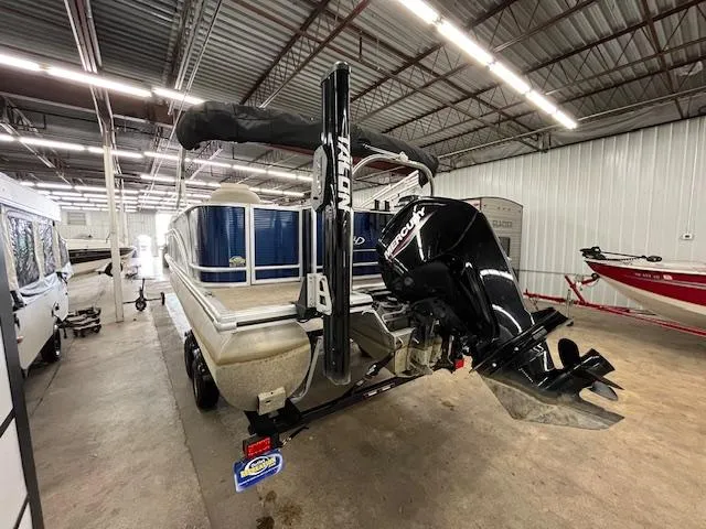 Slide: The Image of 2020 Harris Cruiser 210 pontoon boat in a storage facility, featuring a Mercury outboard motor. - 2