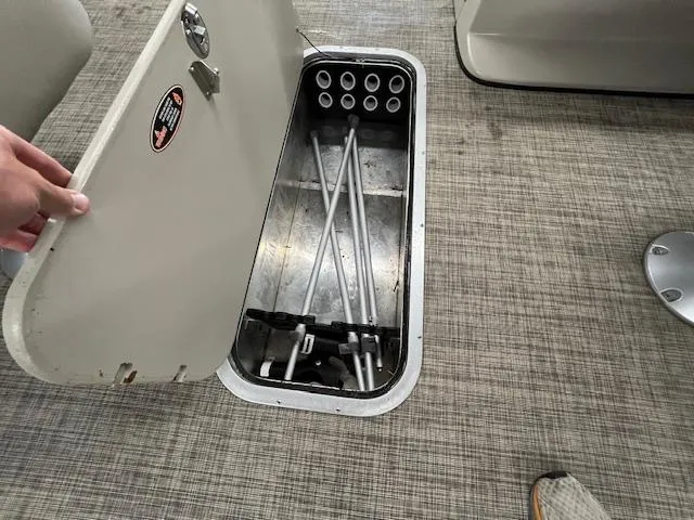 Slide: The Image of Open storage compartment on 2020 Harris Cruiser 210 boat, revealing metal rods inside. - 5