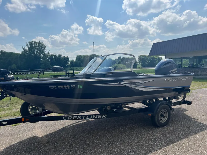 Slide: The Image of 2016 Crestliner Raptor 1850 boat on trailer, parked outdoors under a partly cloudy sky. - 2
