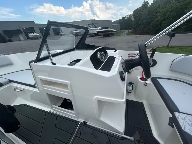 Slide: The Image of 2023 Bayliner Element M17 boat interior with steering wheel and dashboard, parked near storage facility. - 5