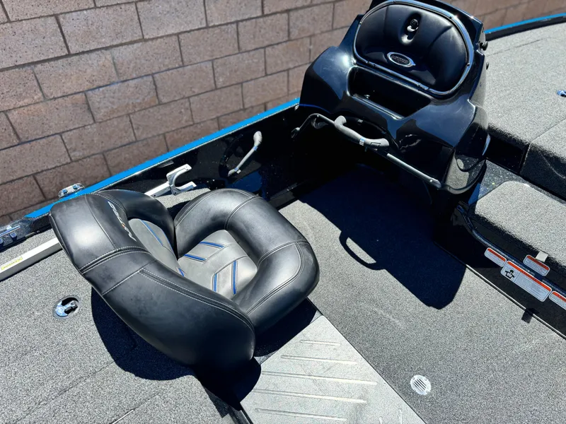 Slide: The Image of 2024 Tracker Z17 boat interior with black seat and console, against brick wall. - 17