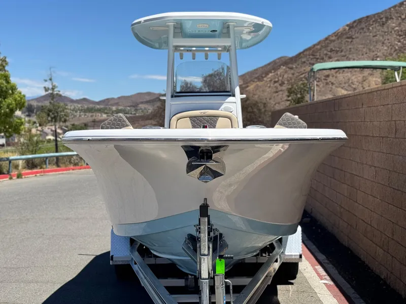 Slide: The Image of 2022 Tidewater 232 CC boat on trailer, parked near mountains under clear blue sky. - 2