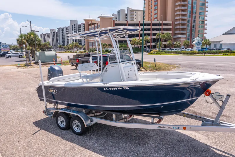 Slide: The Image of 2014 Sea Hunt 196 Ultra Center Console boat on trailer, urban background. - 3