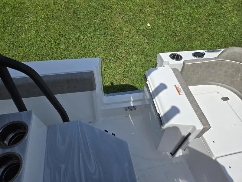 Slide: The Image of 2026 Sea Hunt Ultra 245SE boat interior with seating and cup holders on grass. - 8