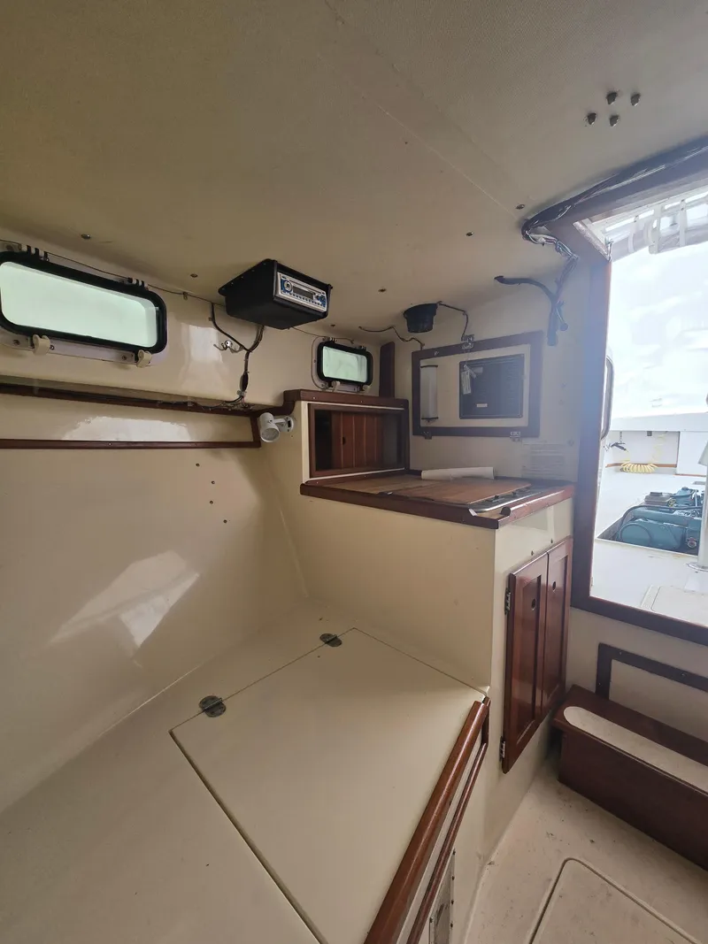Slide: The Image of Interior of a 1993 Fortier 26 boat, featuring compact cabin space with wooden accents. - 11