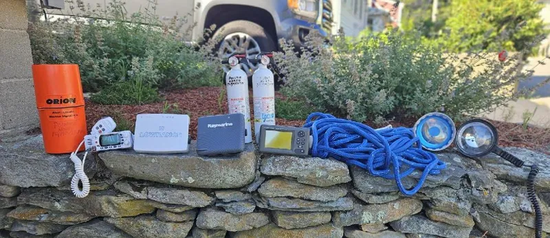Slide: The Image of Assorted boating equipment on stone wall, including safety gear and electronics, for a 1993 Fortier 26. - 18