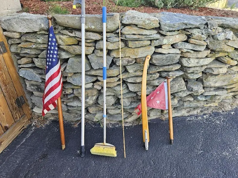Slide: The Image of Tools and flags leaning against a stone wall, including an American flag and broom. - 20