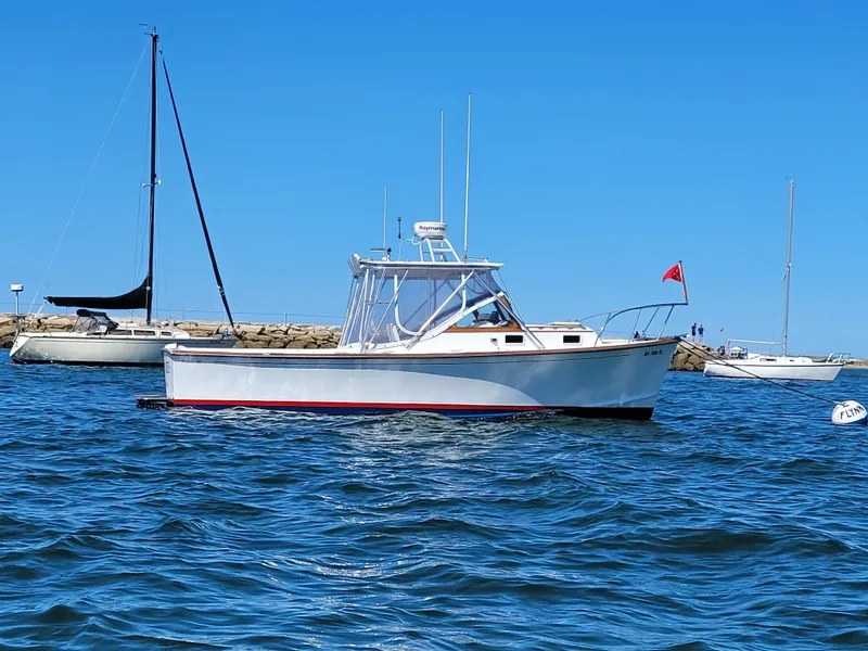 Slide: The Image of 1993 Fortier 26 boat on calm water, clear blue sky, anchored near sailboats. - 3