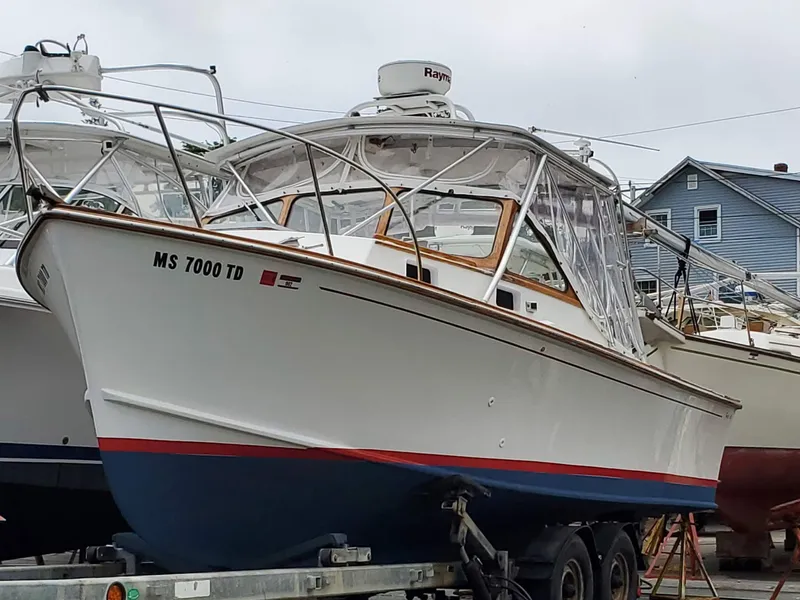 Slide: The Image of 1993 Fortier 26 boat on trailer, white hull with blue and red accents, docked outdoors. - 5