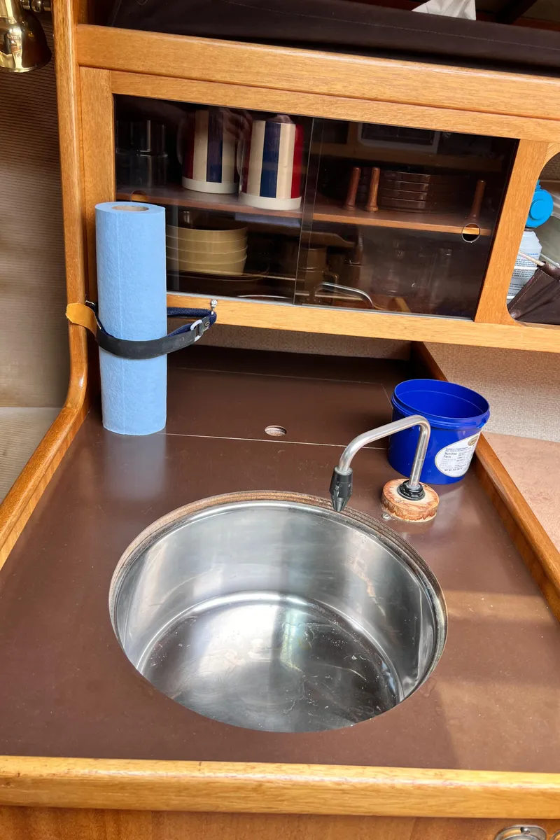 Slide: The Image of 1978 Aphrodite 101 yacht kitchen sink with wooden cabinetry and blue paper towel roll. - 10