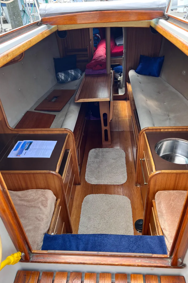 Slide: The Image of 1978 Aphrodite 101 yacht interior with wooden finish, seating, and compact kitchen area. - 6