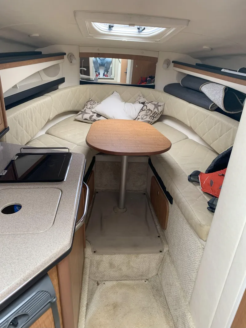 Slide: The Image of Interior of a 2006 Sea Ray 260 Sundancer with cozy seating and a wooden table. - 6