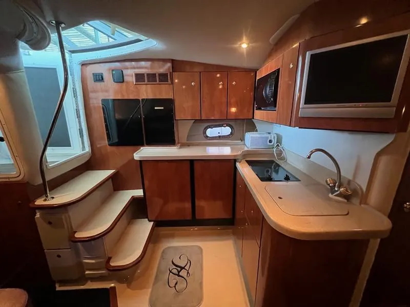 Slide: The Image of 2004 Four Winns 378 yacht interior kitchen with wood cabinets, appliances, and stairs. - 14