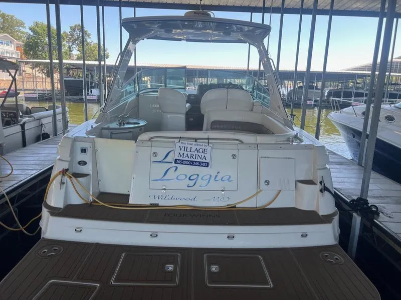 Slide: The Image of 2004 Four Winns 378 boat docked at marina, rear view with seating and signage. - 5