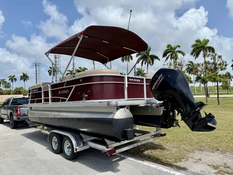 Slide: The Image of 2022 Godfrey Sweetwater 2286 C pontoon boat on trailer, parked near palm trees. - 5