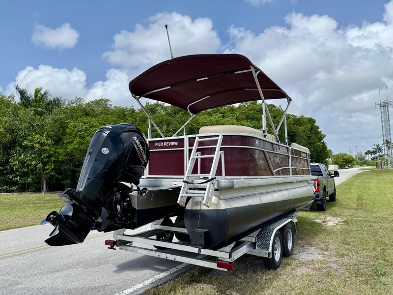 Slide: The Image of 2022 Godfrey Sweetwater 2286 C pontoon boat on trailer, parked roadside under cloudy sky. - 7