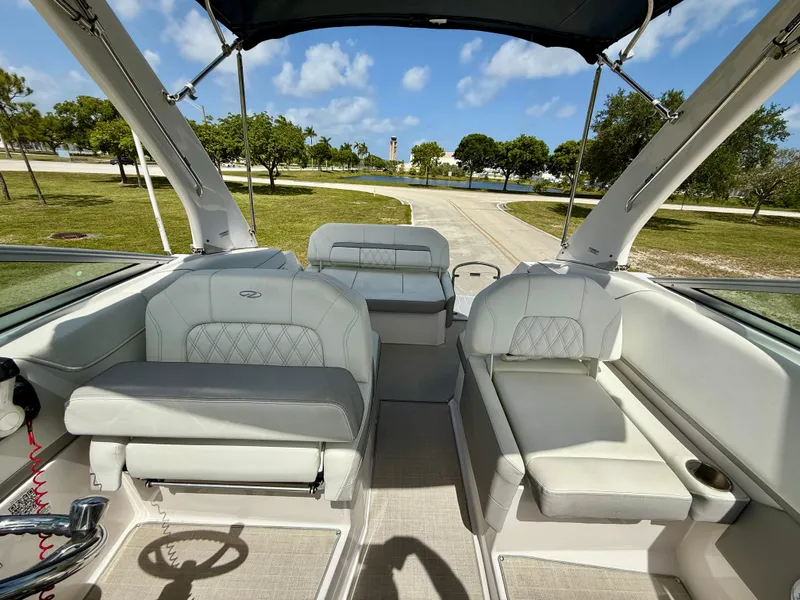 Slide: The Image of 2021 Regal 26 XO boat interior with luxurious seating and canopy, parked near a scenic park. - 12
