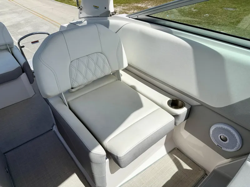 Slide: The Image of 2021 Regal 26 XO boat interior with white seating, cup holder, and speaker. - 14