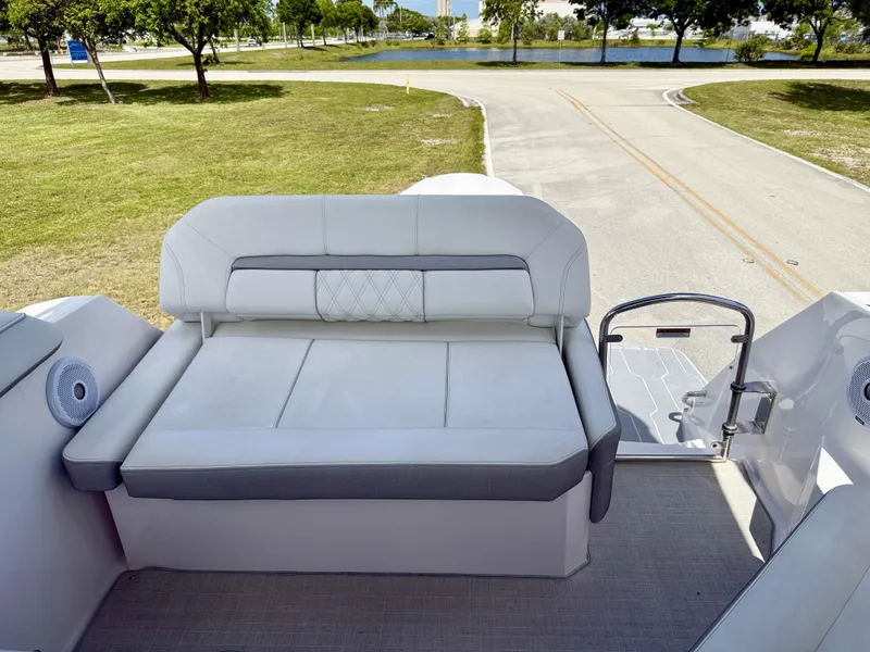 Slide: The Image of 2021 Regal 26 XO boat interior with cushioned seating and speakers, parked near a road. - 19