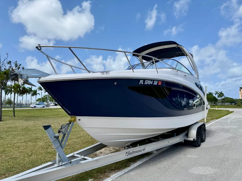 Slide: The Image of 2021 Regal 26 XO boat on trailer, parked outdoors under a blue sky. - 2