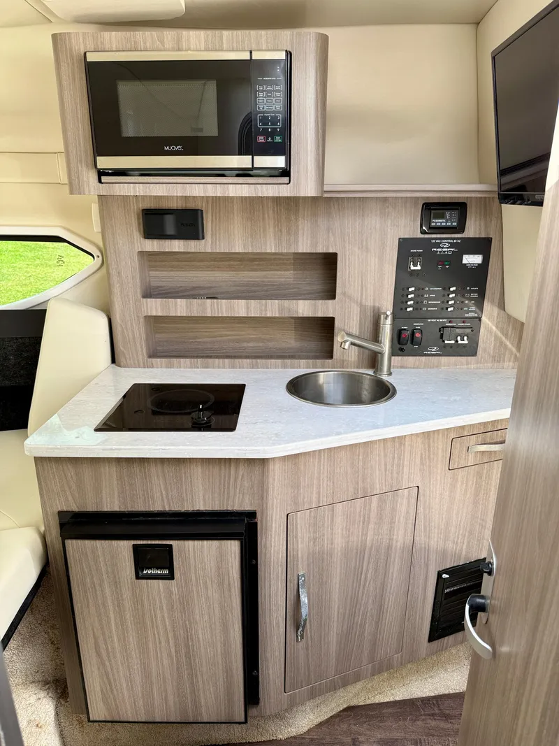 Slide: The Image of 2021 Regal 26 XO boat interior kitchen with microwave, sink, stove, and mini fridge. - 34