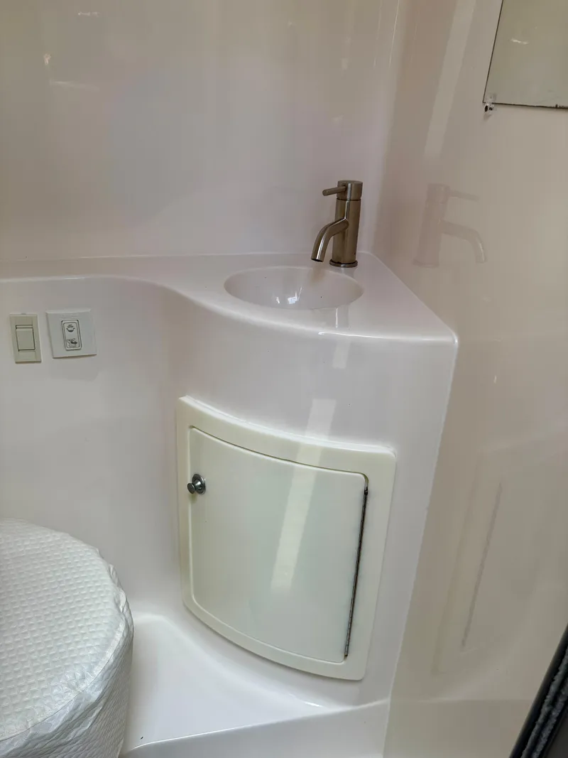Slide: The Image of Compact bathroom in a 2021 Regal 26 XO boat with sink and storage cabinet. - 38