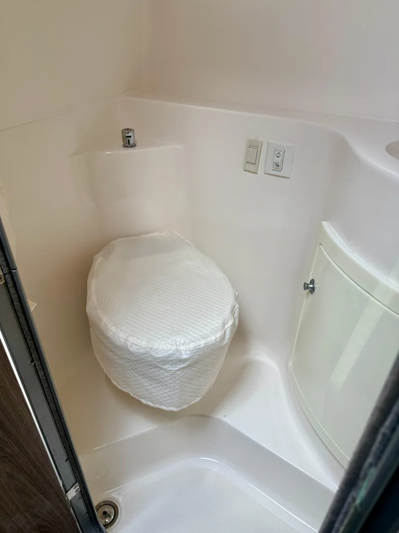 Slide: The Image of Compact bathroom in 2021 Regal 26 XO boat, featuring a covered toilet and storage cabinet. - 39