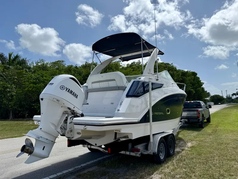 Slide: The Image of 2021 Regal 26 XO boat with Yamaha engine on trailer, parked roadside under blue sky. - 4