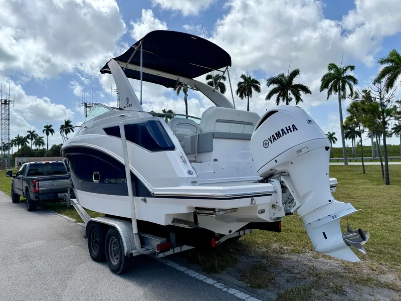 Slide: The Image of 2021 Regal 26 XO boat on trailer with Yamaha engine, parked near palm trees. - 6