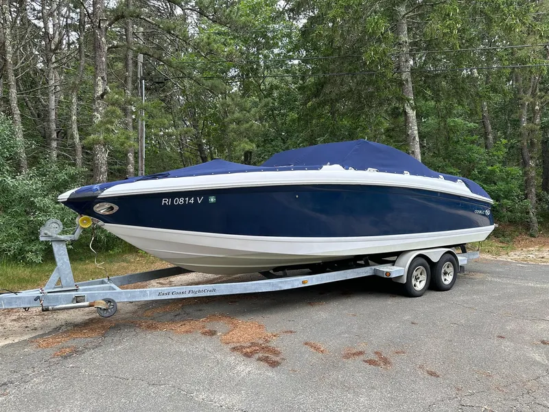 Slide: The Image of 2010 Cobalt 262 boat on trailer, covered, parked in wooded area. - 2