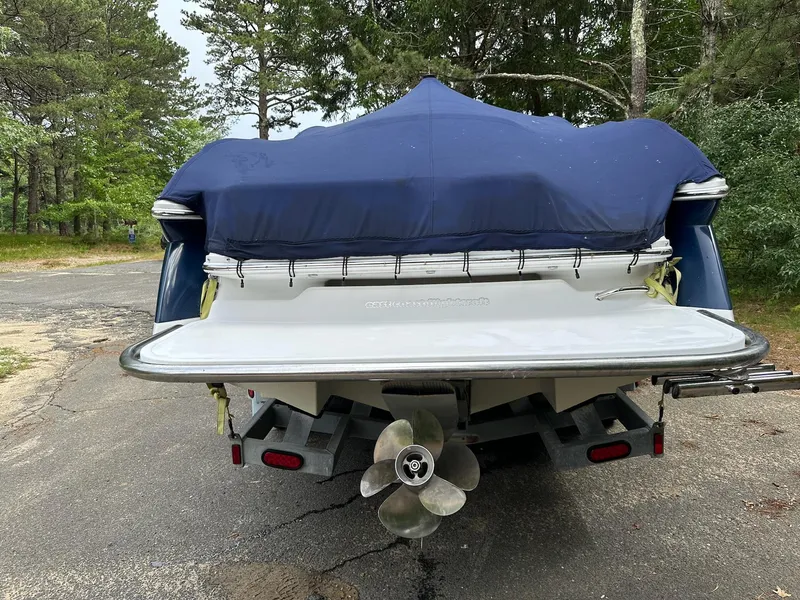 Slide: The Image of 2010 Cobalt 262 boat with blue cover, parked on a trailer in a wooded area. - 4