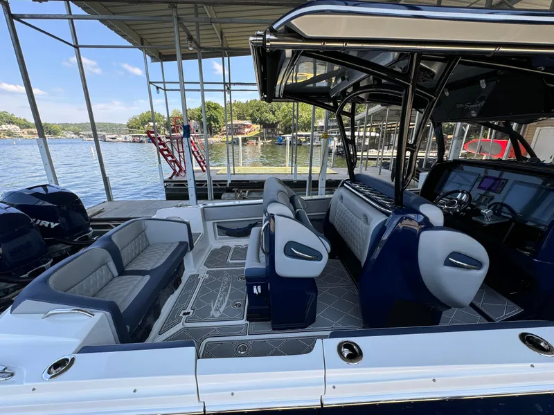 Slide: The Image of 2019 Nor-Tech 390 Sport Center Console boat interior with seating and controls, docked by a lake. - 15