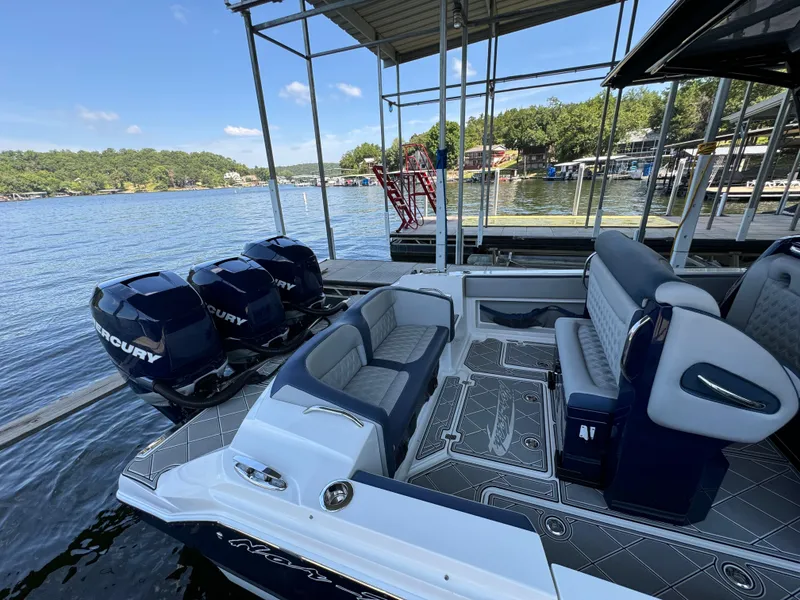 Slide: The Image of 2019 Nor-Tech 390 Sport Center Console boat with triple Mercury engines docked by a lake. - 16