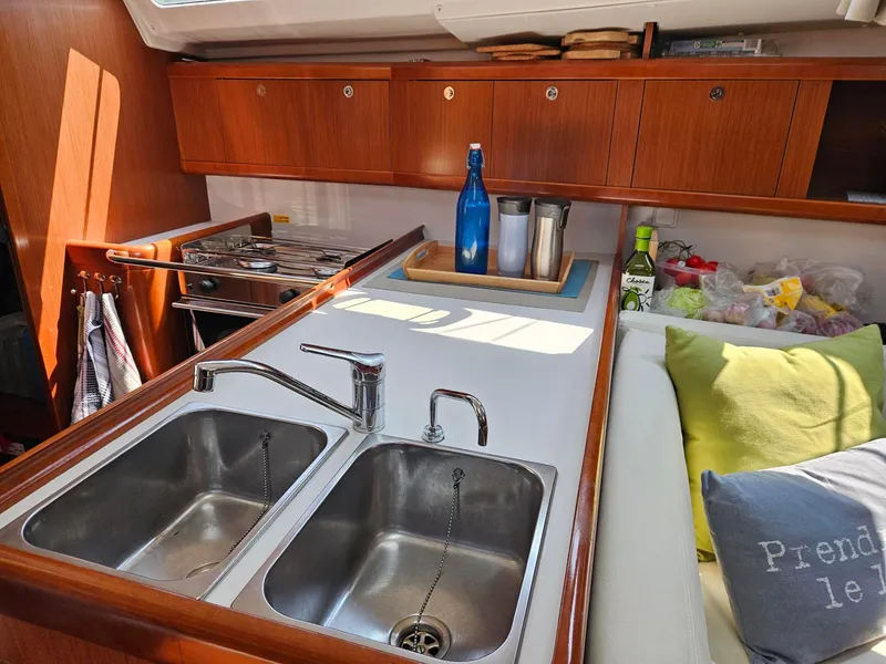 Slide: The Image of Cozy kitchen area in a 2012 Beneteau Oceanis 37 sailboat, featuring dual sinks and wooden cabinetry. - 17
