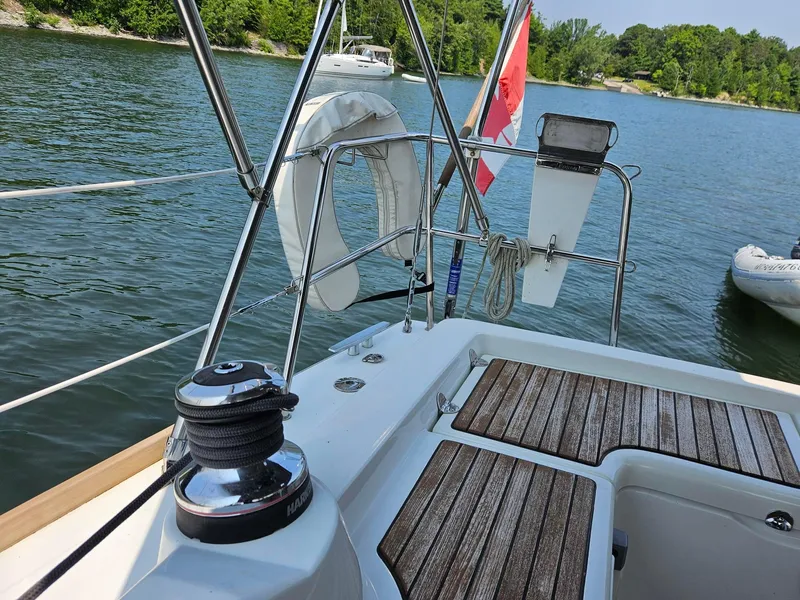 Slide: The Image of Beneteau Oceanis 37 sailboat cockpit with wooden deck, Canadian flag, and scenic lake view. - 5
