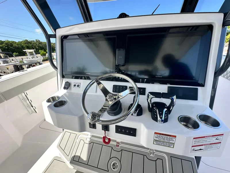 Slide: The Image of 2026 Twin Vee 400 GFX2 CC boat dashboard with dual screens and steering wheel. - 15