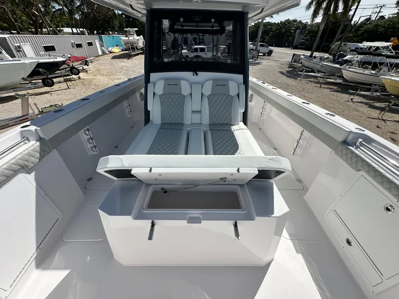 Slide: The Image of 2026 Twin Vee 400 GFX2 CC boat interior with seating and storage, docked outdoors. - 19
