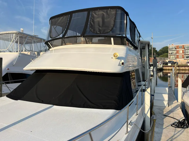 Slide: The Image of 2000 Carver 406 Aft Cabin Motor Yacht docked at marina, featuring black canvas covers. - 2