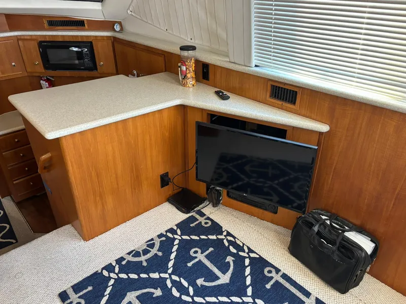 Slide: The Image of Interior of 2000 Carver 406 Yacht with TV, counter, and nautical-themed rug. - 22