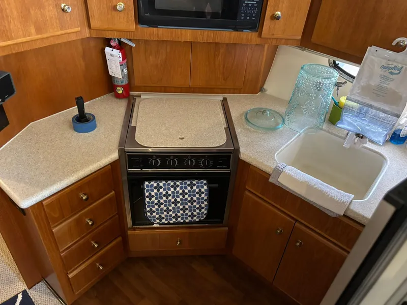 Slide: The Image of Compact kitchen in 2000 Carver 406 Aft Cabin Motor Yacht with stove, sink, and wooden cabinets. - 26