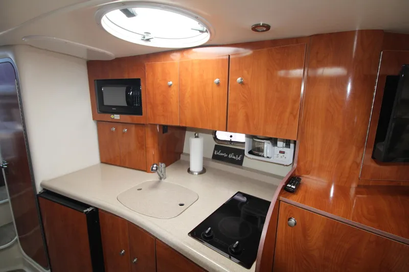 Slide: The Image of 2004 Four Winns 348 Vista yacht kitchen with wood cabinets, microwave, and stovetop. - 22
