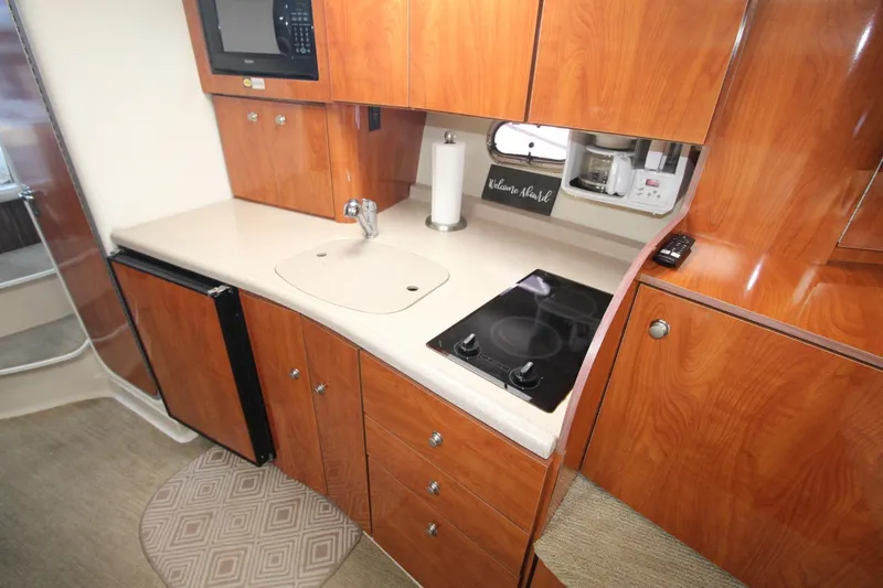 Slide: The Image of 2004 Four Winns 348 Vista yacht kitchen with wood cabinets, sink, stove, and microwave. - 23