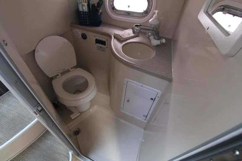 Slide: The Image of Compact bathroom in 2004 Four Winns 348 Vista boat, featuring toilet, sink, and window. - 34