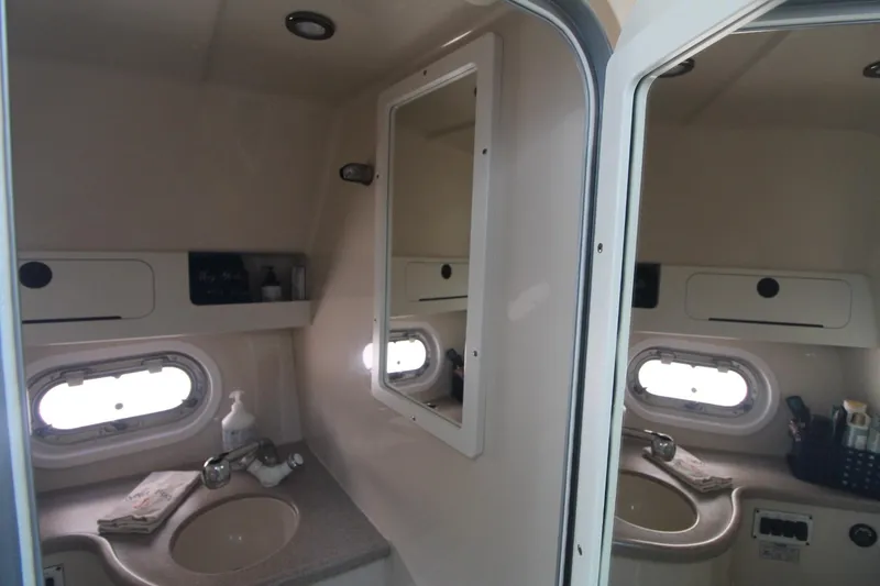 Slide: The Image of 2004 Four Winns 348 Vista bathroom with sink, mirror, and porthole window. - 35
