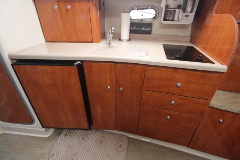 Slide: The Image of 2004 Four Winns 348 Vista boat kitchen with wood cabinets, sink, and stovetop. - 39