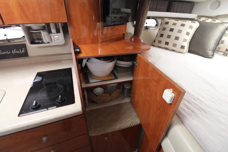 Slide: The Image of 2004 Four Winns 348 Vista interior with kitchenette, open cabinet, and cozy bedding. - 43