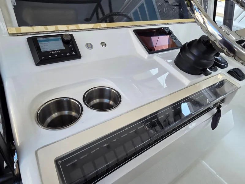 Slide: The Image of 2023 SeaVee 37 Z boat dashboard with controls, cup holders, and audio system. - 16